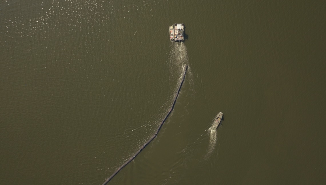 Boat pulling pipe through lake