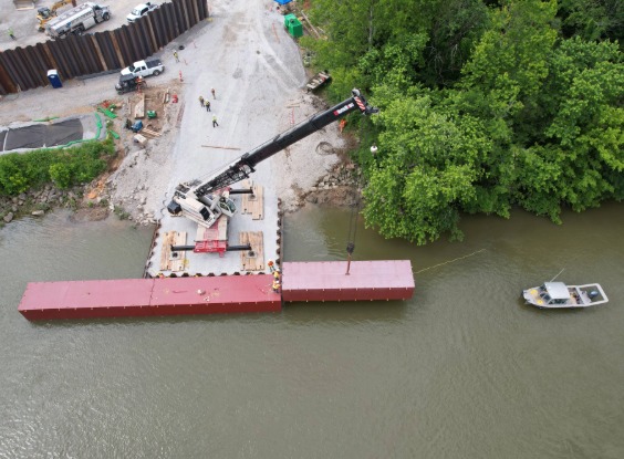 Crane lowering barge into river