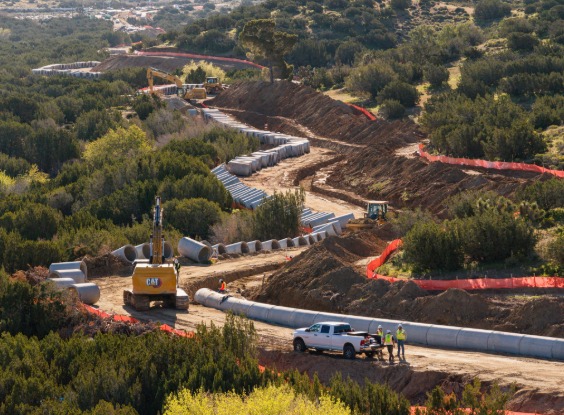 Pipe set up along road with excavator driving